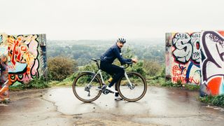 A white man on an all road bike on a hilltop viewpoint