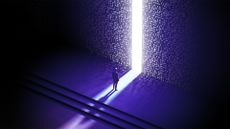 Digital world concept image showing a man standing before digitized wall with small opening and light shining out from other side.