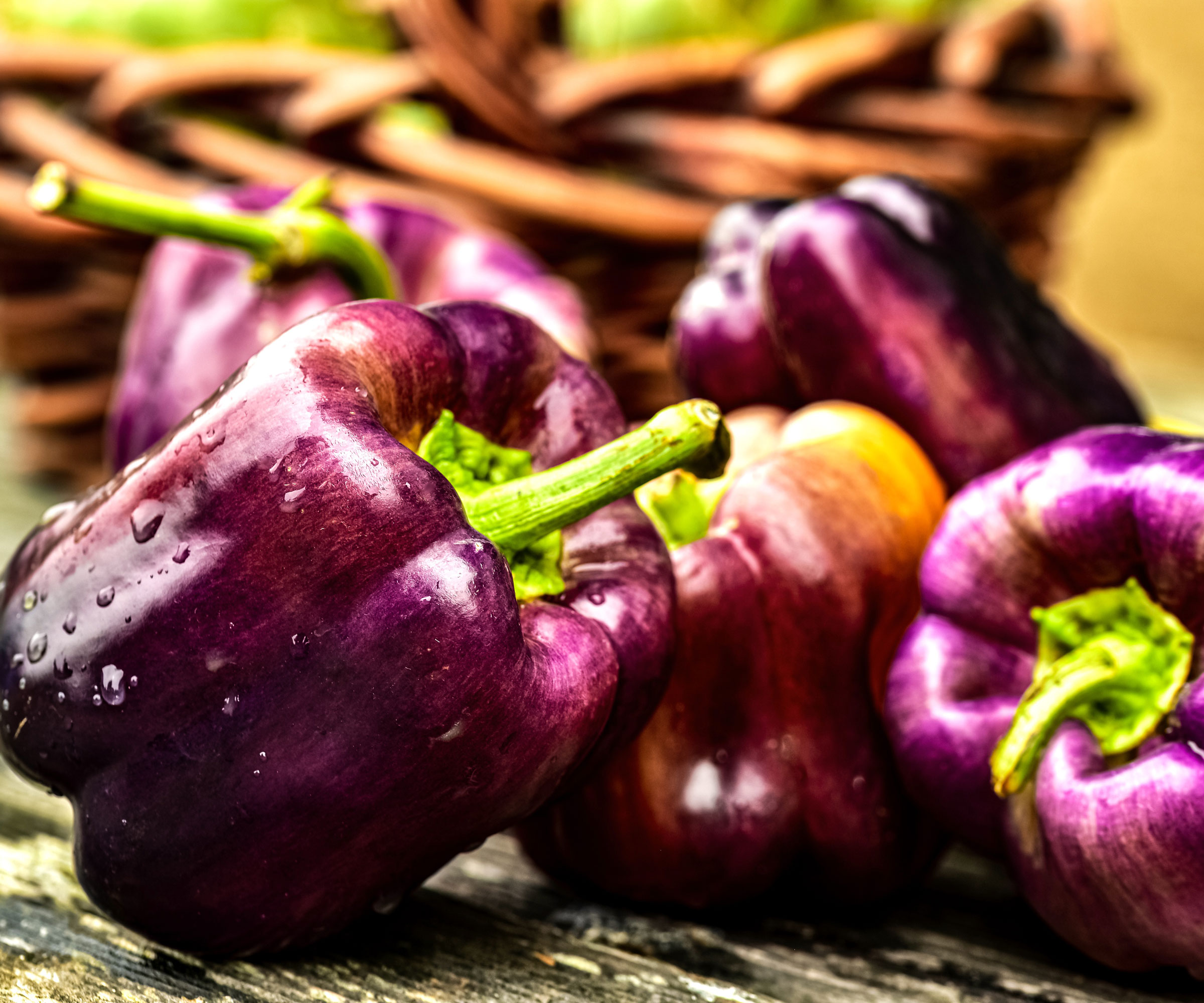 purple bell peppers freshly harvested and sitting on wooden table