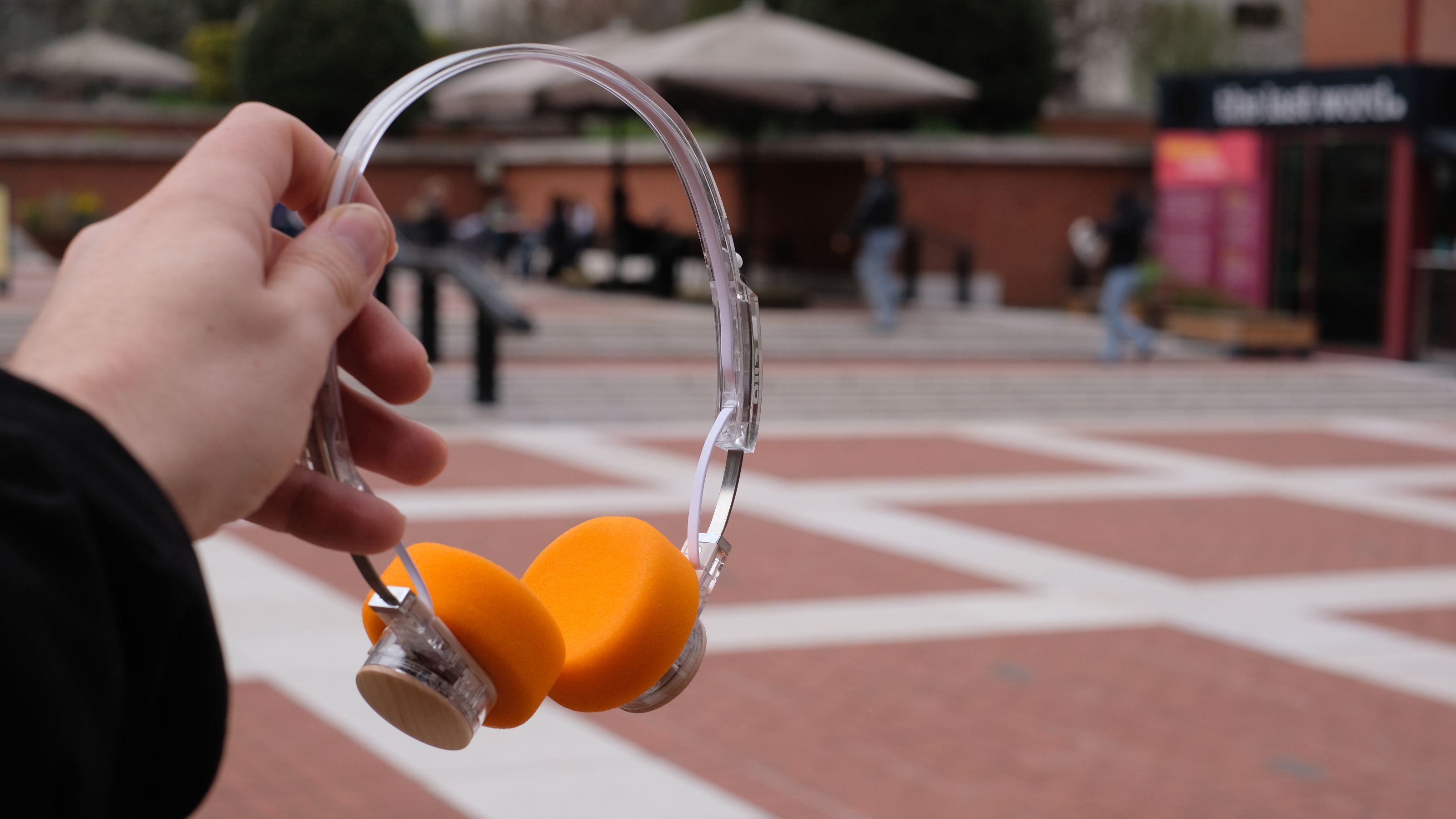 A photograph of the FiiO EH11 over-ear headphones with a transparent frame and orange foam earpads.