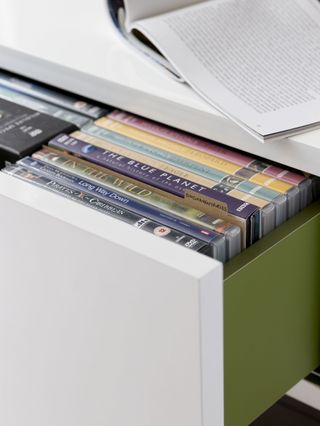 Open drawer with white front with DVDs inside