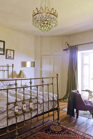 bedroom with cast iron bed and ornate light persian rug and wooden flooring