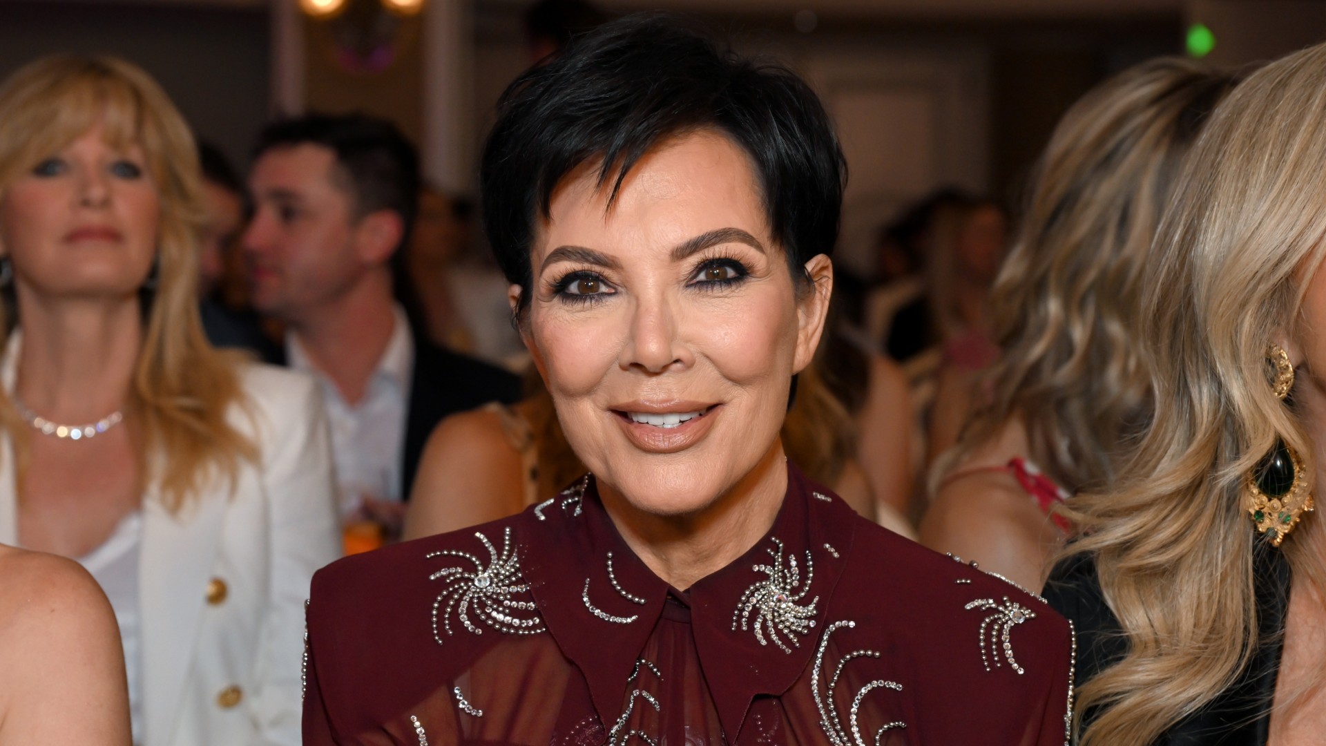 a woman with short dark hair sitting in a crowd of people