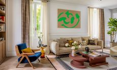 Living room with beige sofa, terracotta two-piece geometric coffee table, electric blue armchair and white, black and pale pink patterned rug