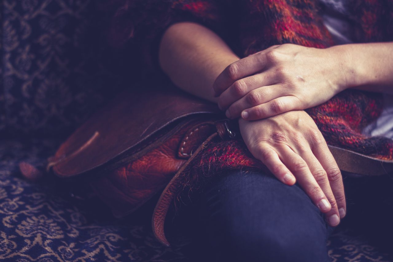 A woman sits with folded hands.