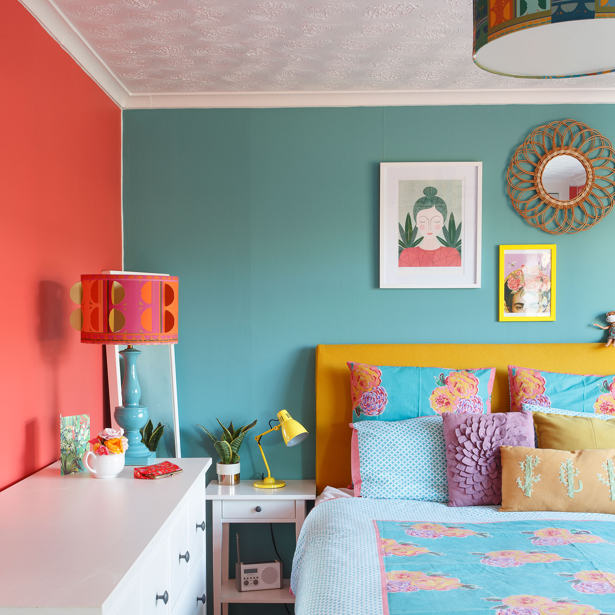 bedroom with blue and coral walls, yellow headboard and patterned cushions