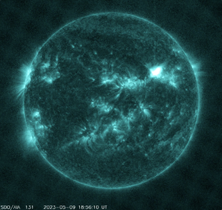 the sun as seen in an infrared image. bright fiery tendrils branch outward from a dark green ball of fire