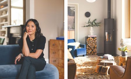 A side-by-side composition featuring designer Susan Chesney sitting on a blue velvet sofa, next to a sunlit living room with a modern fireplace and rustic wood accents