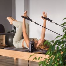 A woman on one of the best at-home Reformer Pilates machines