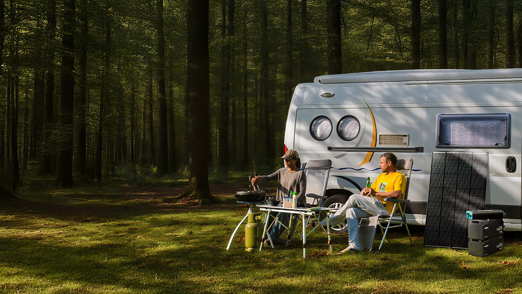 2 men set outside caravan on seats in forest