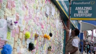 Notes are pinned on a ‘peace wall’ on a boarded-up window of Poundland