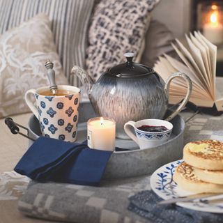 tray with tea crumpets and scented candle