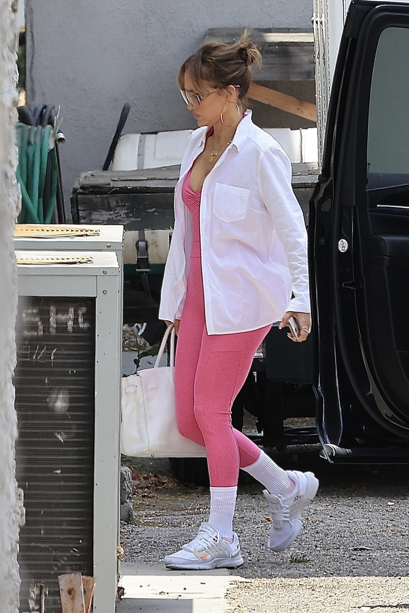 Jennifer Lopez stepped outside on her way to a dance studio, styling pink leggings with white trainers, white socks and a white cotton shirt.