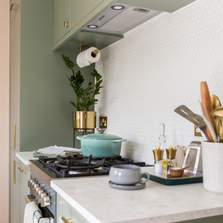 Kitchen stove with caserole dish. Next to it is a salt and pepper grinder on the side and a jar of kitchen utensils