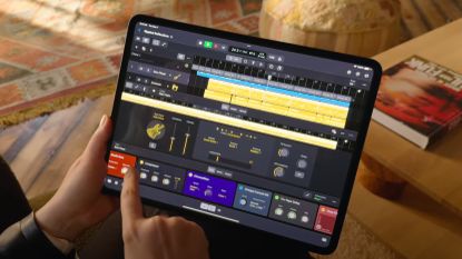 A hand holding an iPad that's running Logic Pro
