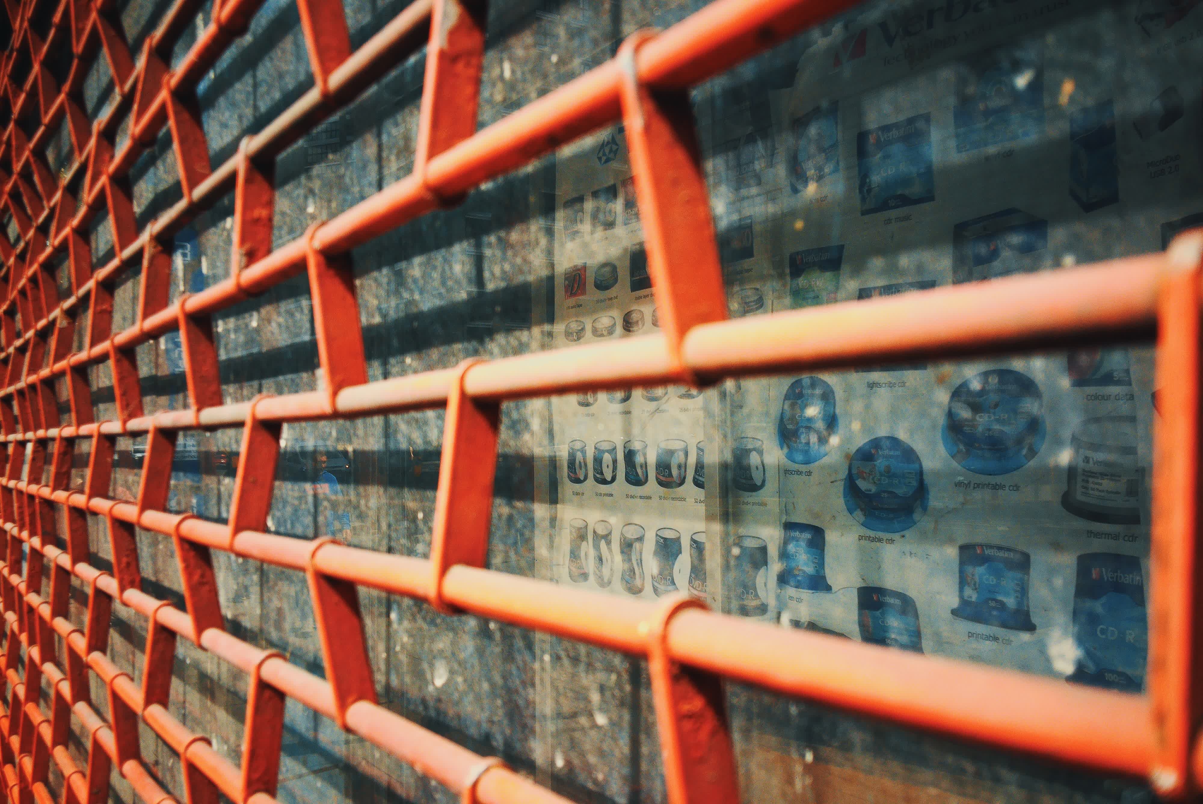 Photograph taken with the RewindPix digital compact showing faded posted behind a grated orange shutter in a shop window