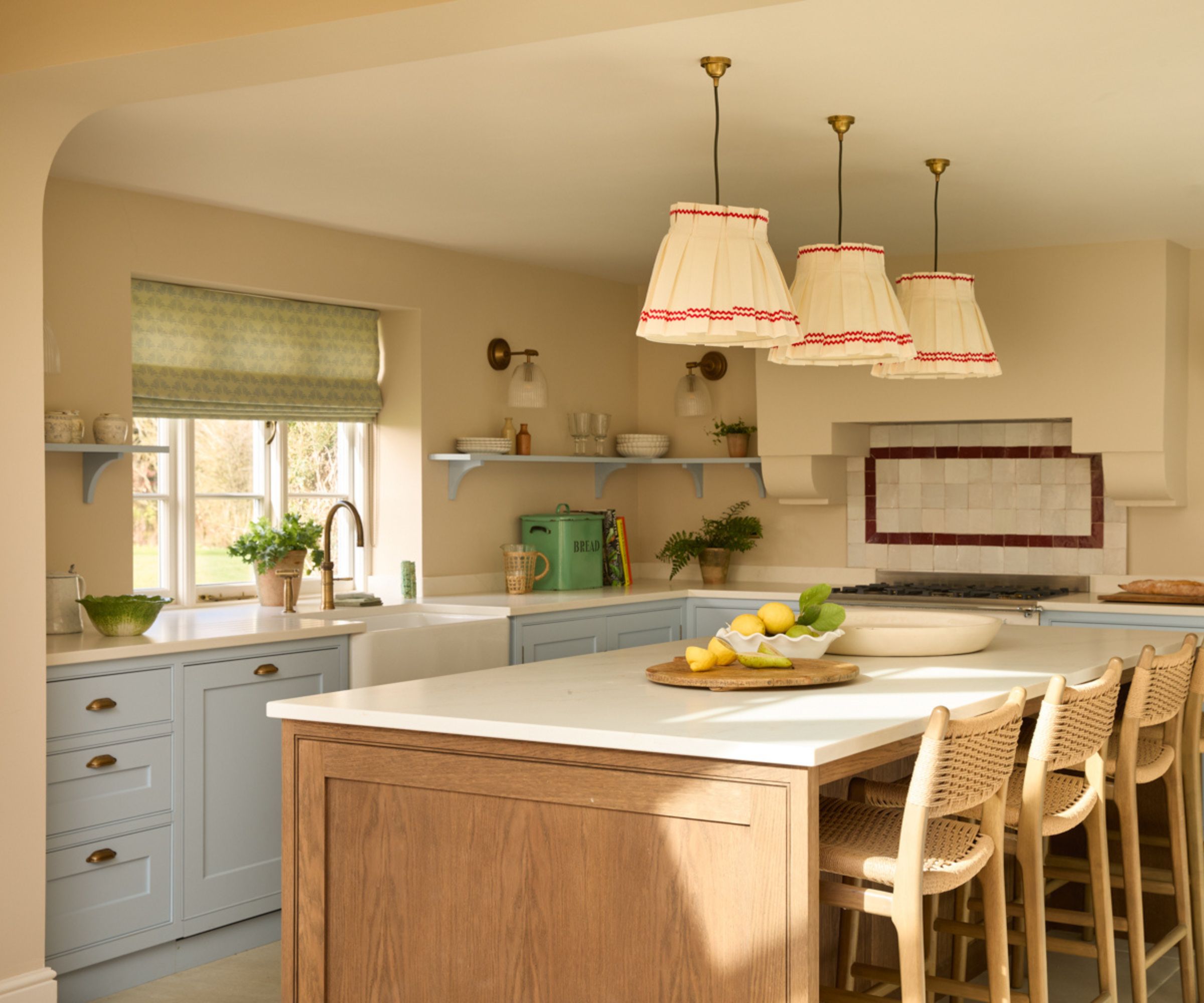 A large kitchen with light blue cabinets, light yellow walls, and a wooden island