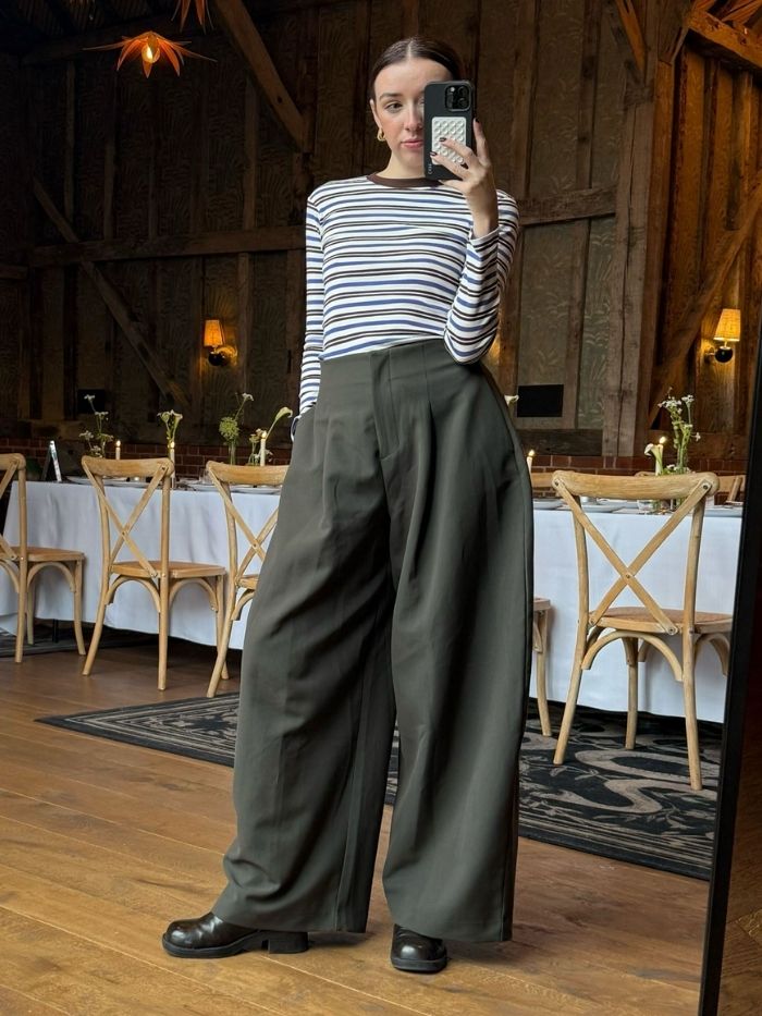 Woman wears striped top and barrel leg tailored trousers