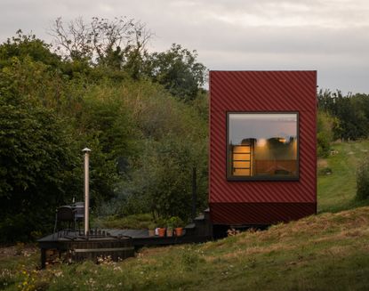 A small red cabin home in a countryside setting