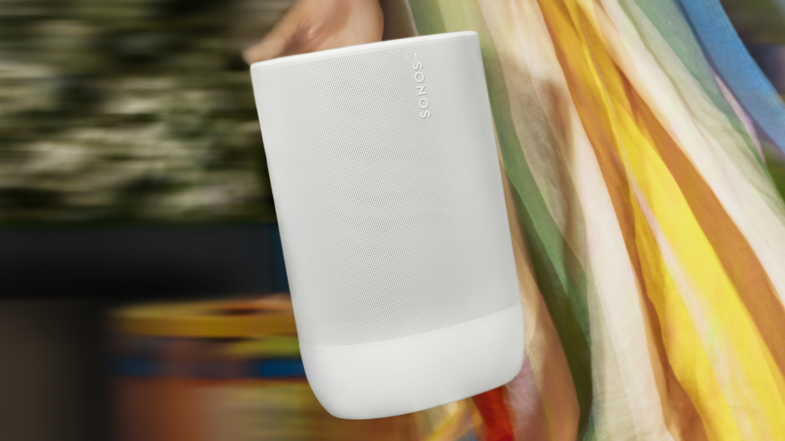 Sonos Move 2 held in a hand, against a blurred background that implies someone is dancing