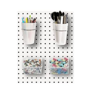 A pegboard with pots and trays with stationery in it