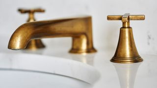 golden brass sink tap on marble counter