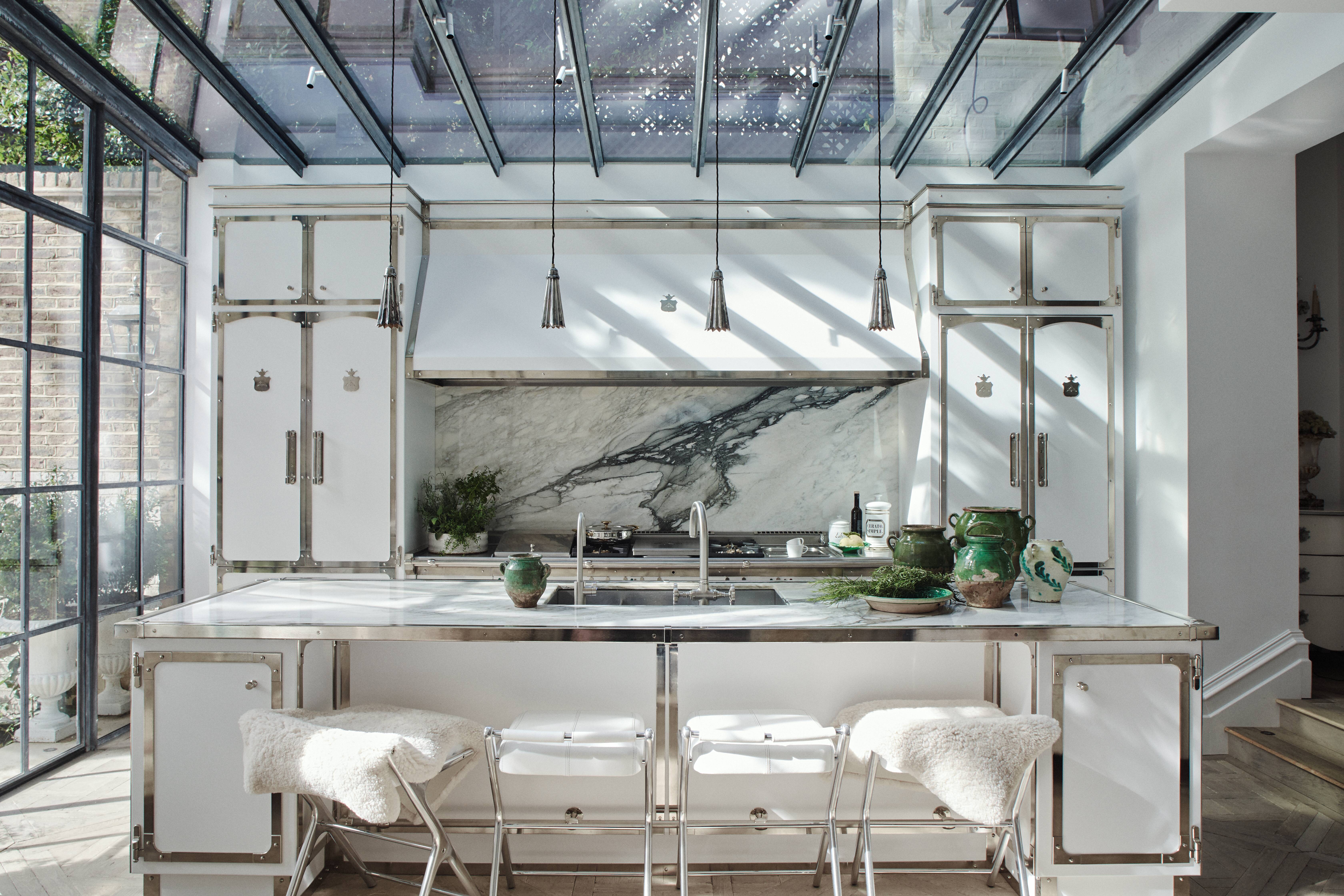 White kitchen cabinets and kitchen island with metal framings and white marble backsplash.