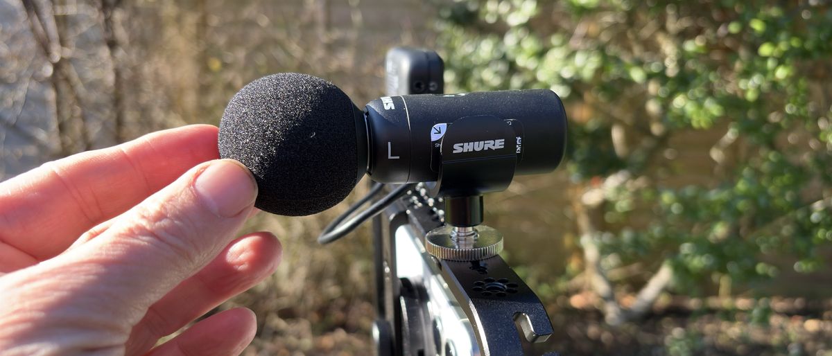 Shure MoveMic 88+ microphone attached to the top of an iPhone being adjusted by a hand
