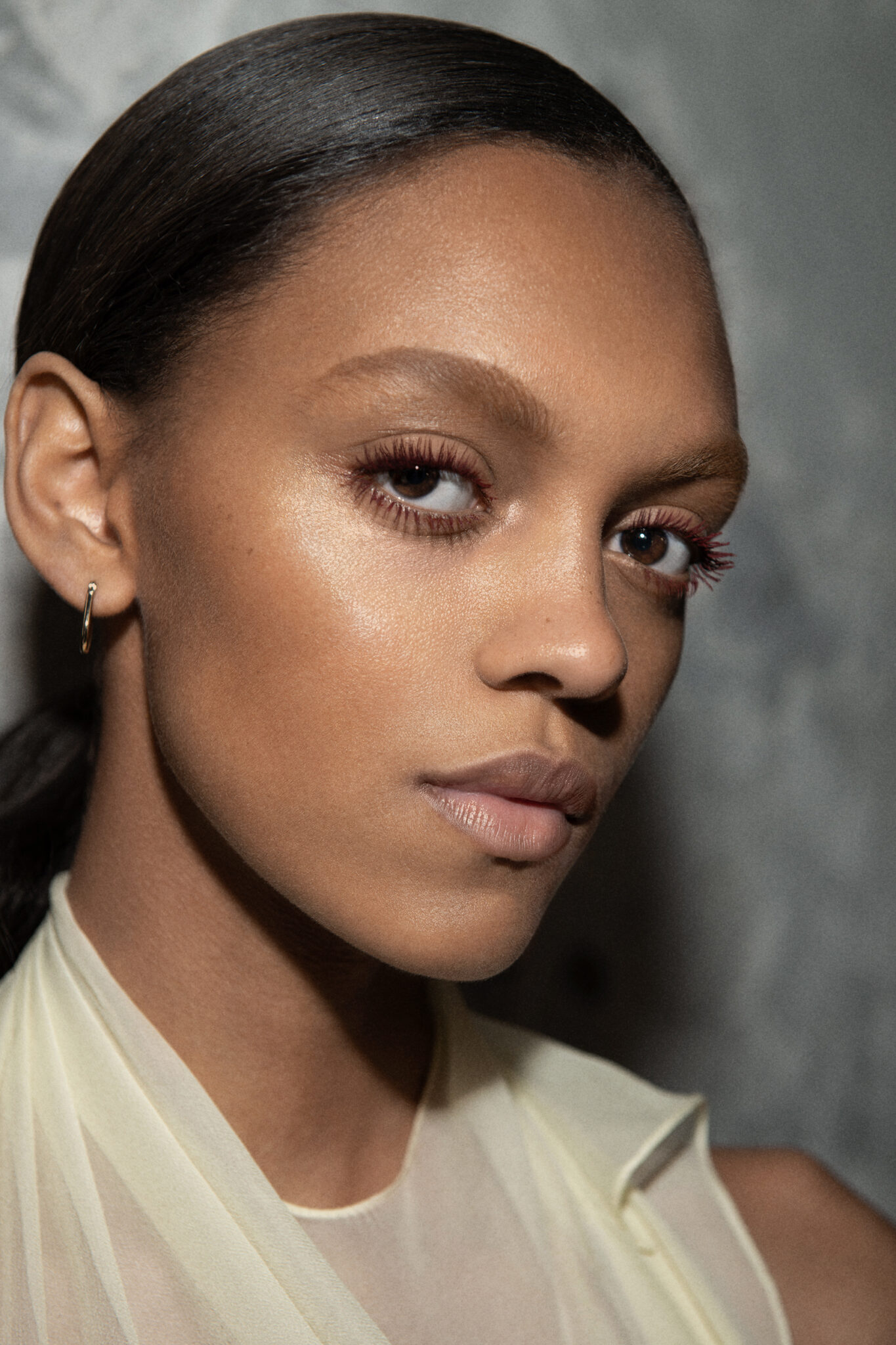 A model at the Victoria Beckham Fall-Winter 2025-2026 show during Paris Fashion Week wearing burgundy mascara.