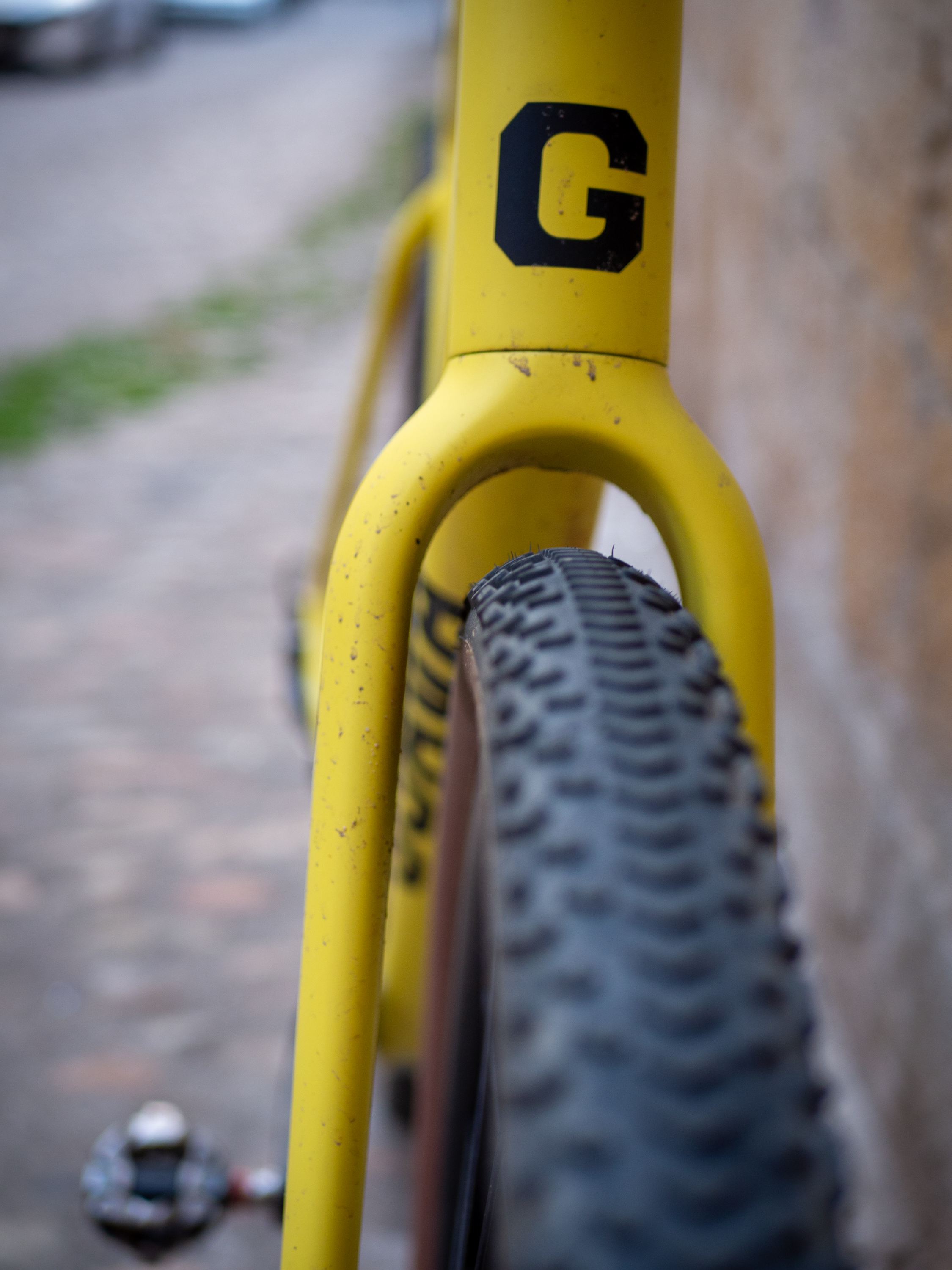 A yellow Guava Spot gravel bike leans against a wall