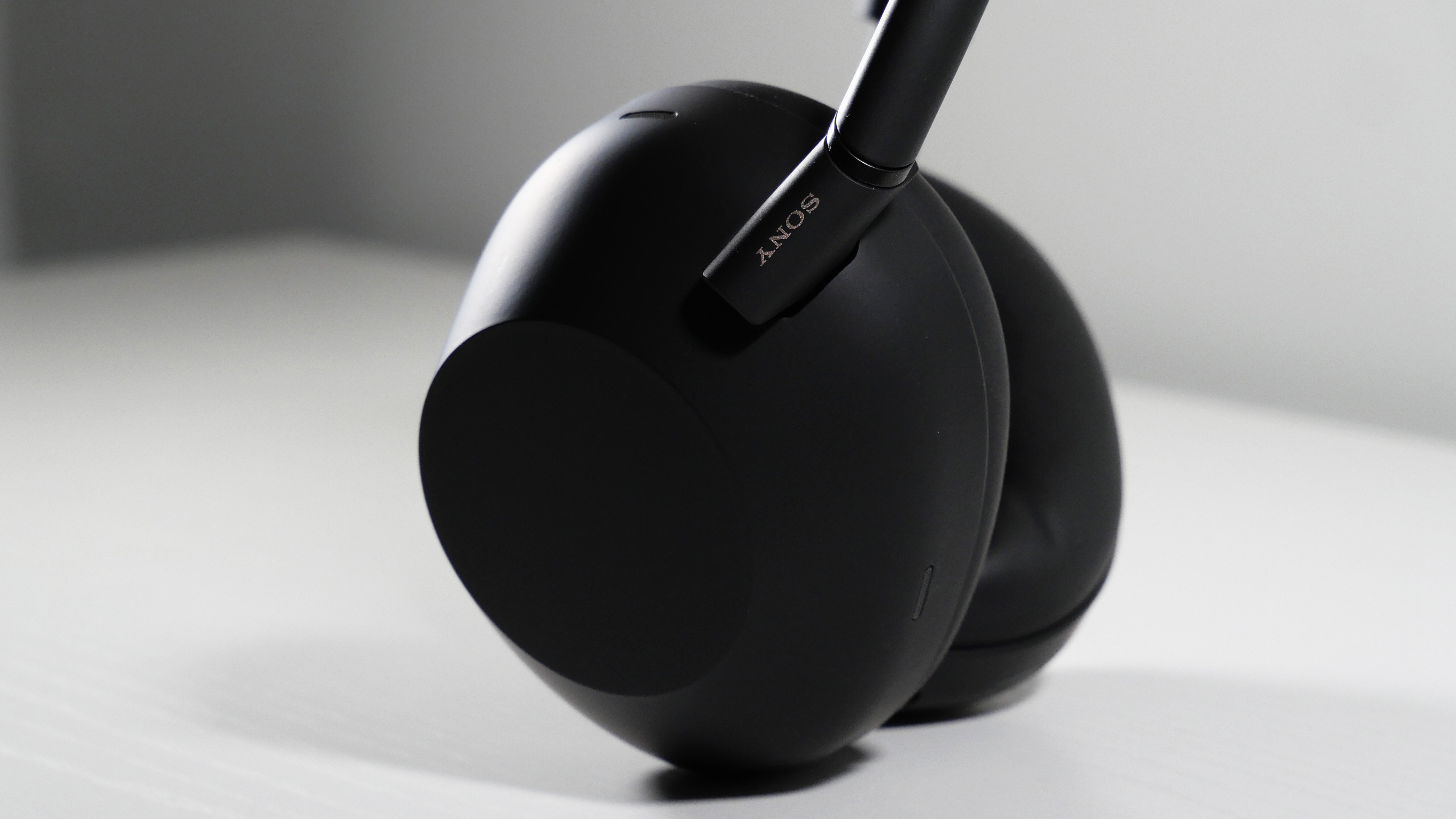 Sony WH-1000XM6 standing up on a white desk at an angle, highlighting its right earcup.