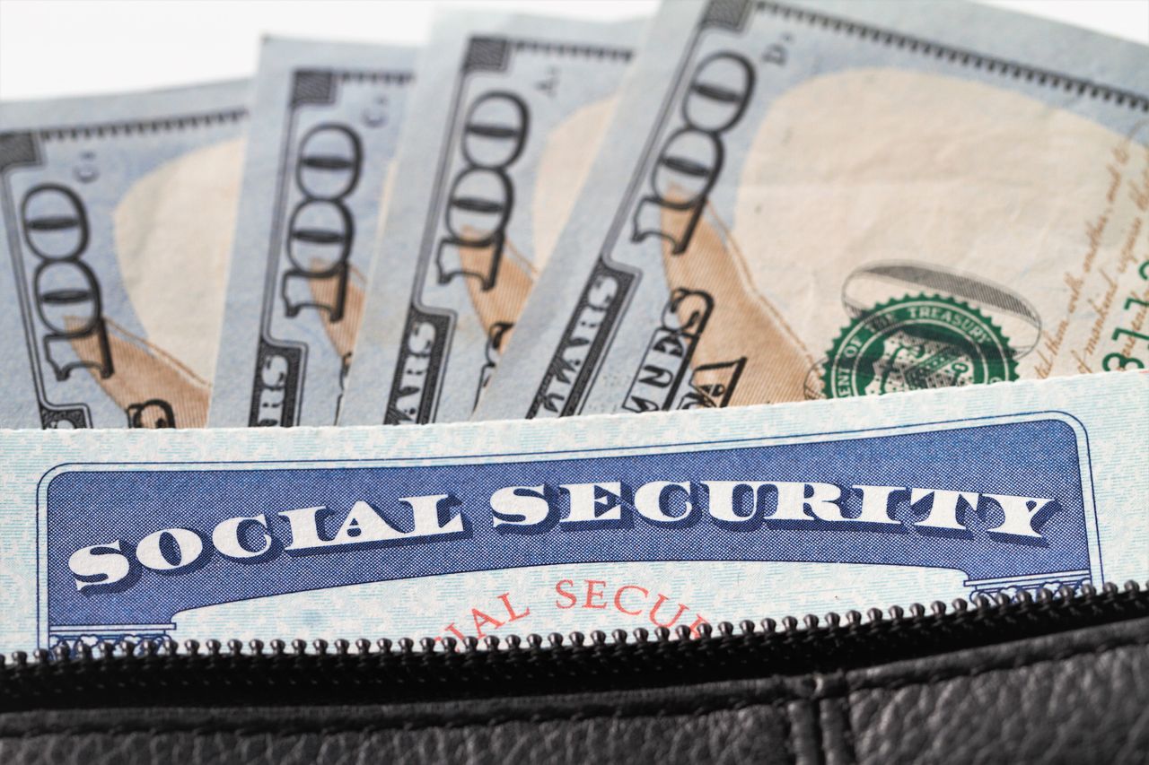 Social security card and hundred dollar bills in handbag pocket on red background.Finance, retirement and consumerism concept image.