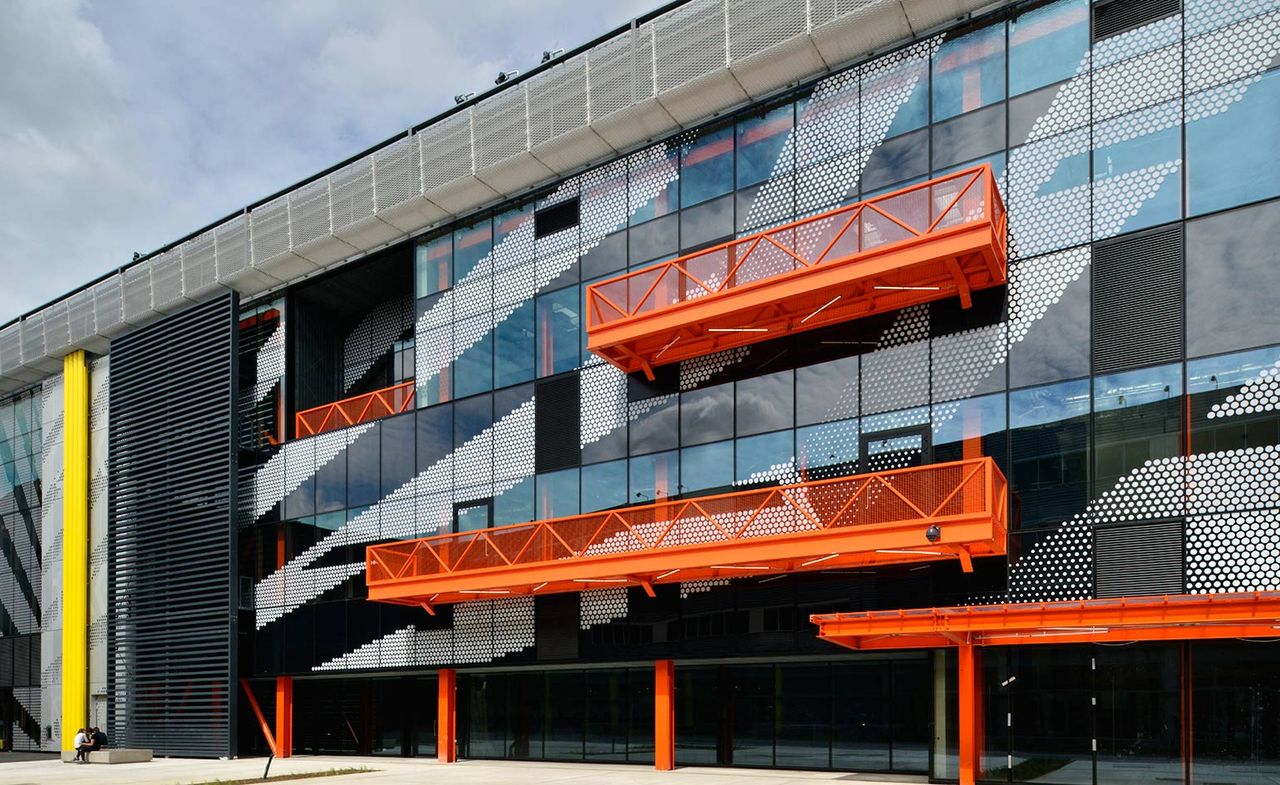 The exterior of the campus. All glass exterior with bright orange &amp; yellow metal elements.The exterior of the campus. All glass exterior with bright orange &amp; yellow metal elements.