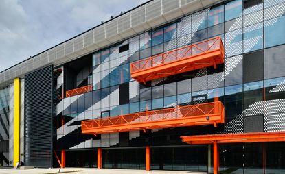 The exterior of the campus. All glass exterior with bright orange & yellow metal elements.The exterior of the campus. All glass exterior with bright orange & yellow metal elements.