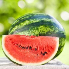 A slice of watermelon and a whole watermelon outdoors