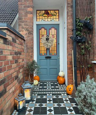 Blue front door with floor tiles, pumpkins and lanterns