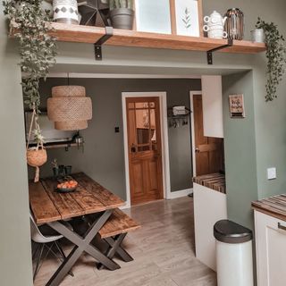 Green kitchen with wooden table and plants on shelves