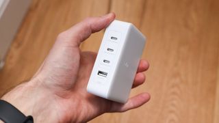 Belkin BoostCharge Pro 140W 4-Port GaN Wall Charger held in a hand above a wooden floor