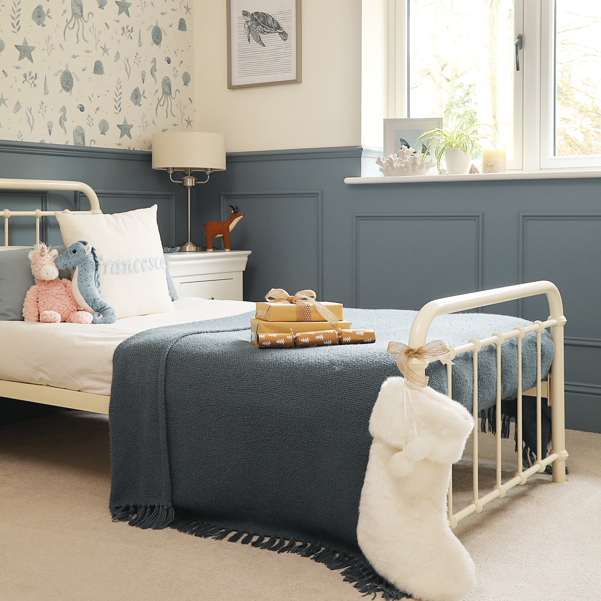a childs bedroom decorated in a dark blue shade with wall panelling, a metal bed and. Christmas stocking