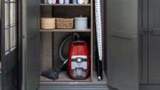 a vacuum cleaner in the base of a cabinet