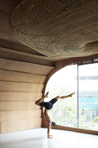 A person practicing yoga in Vikasa's studio space featuring wood panels and a large window