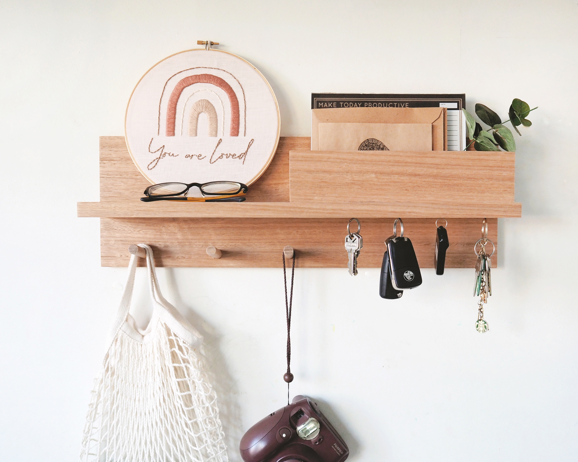 Wooden shelf with pegs and hooks for keys, bags, and compartment for mail.