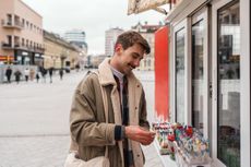 Young man tourist holding travel money to buy candy at a street kiosk in the city