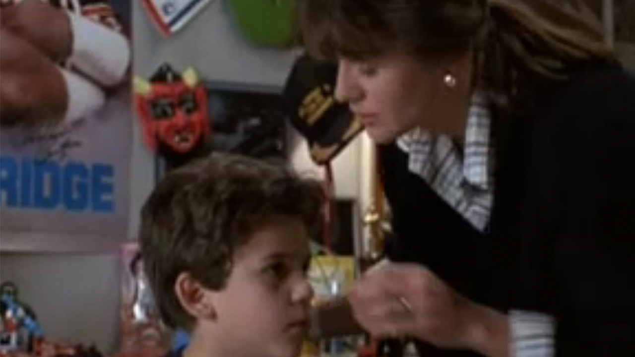 Fred Savage in bed with a famous hat behind him