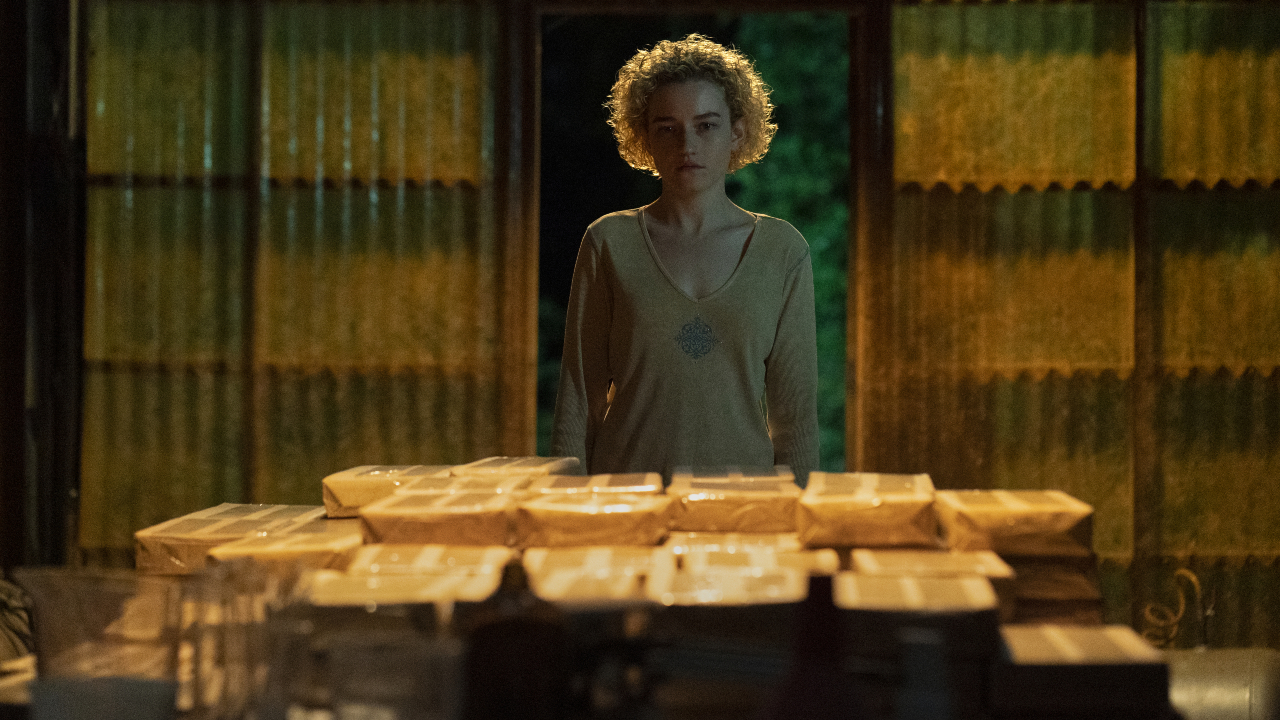 Julia Garner is in front of a table full of packages in Ozark.