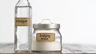 Close-up of baking soda and vinegar on table against white background
