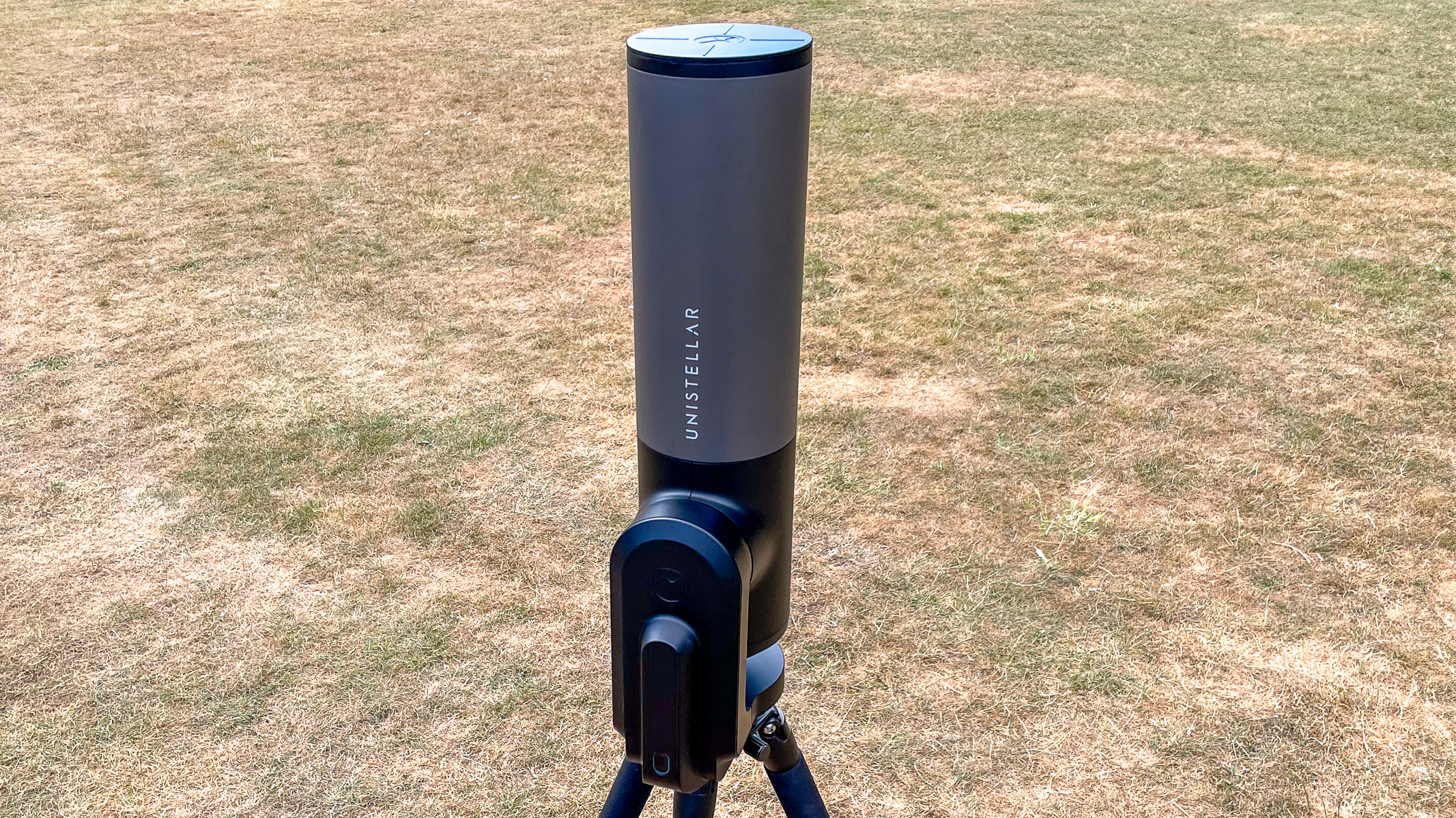 The Unistellar eVscope 2 pointing straight up with grass in the background.