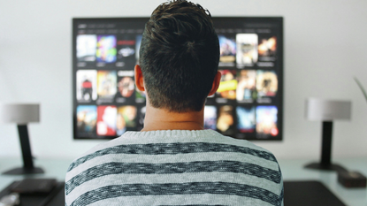 Best TVs under $1000: image depicts man sat in front of TV with Netflix on