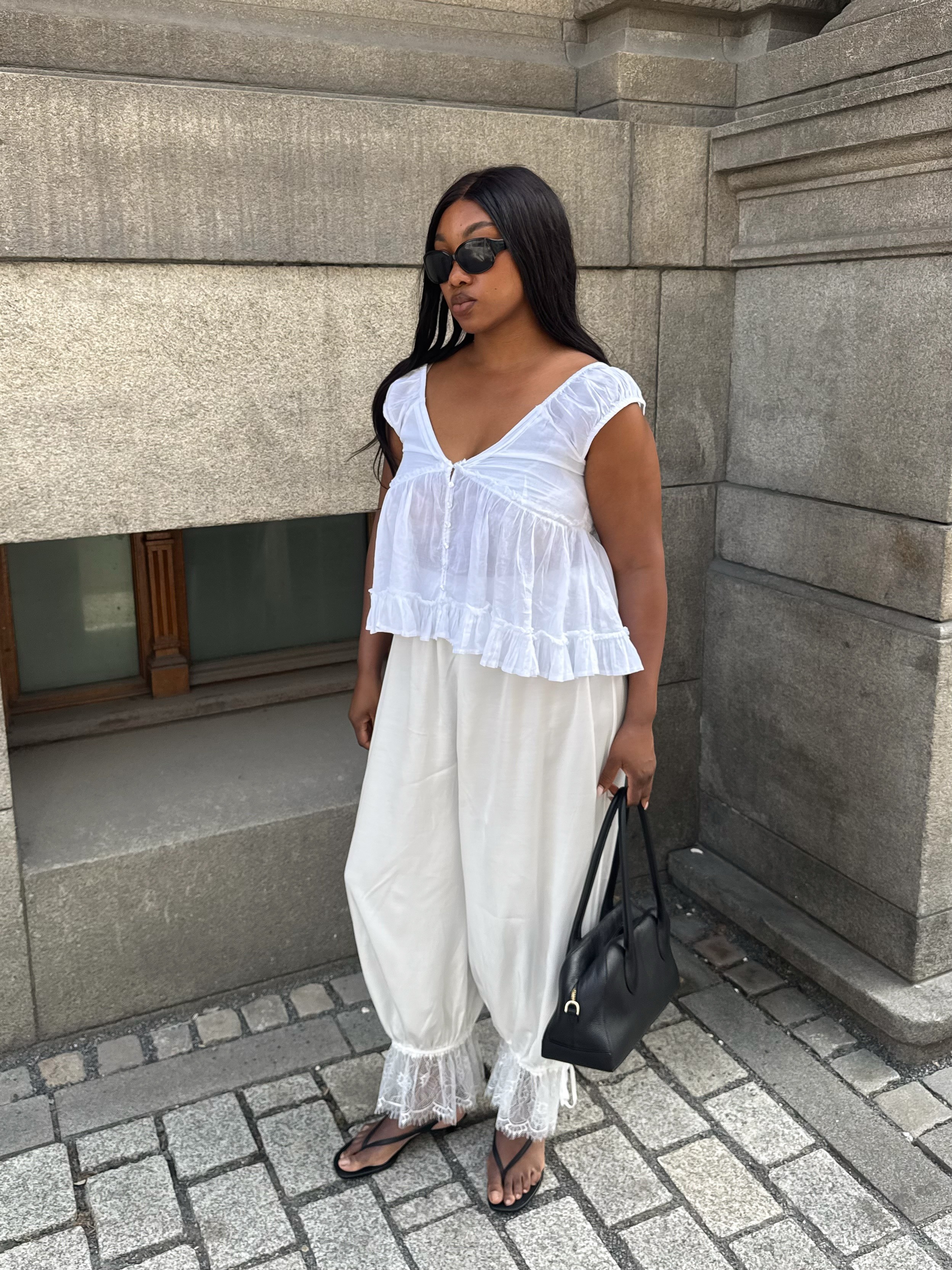 A woman wearing a floaty white outfit with a dark brown, straight hairstyle