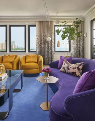 living room with blue rug, yellow chair and purple couch